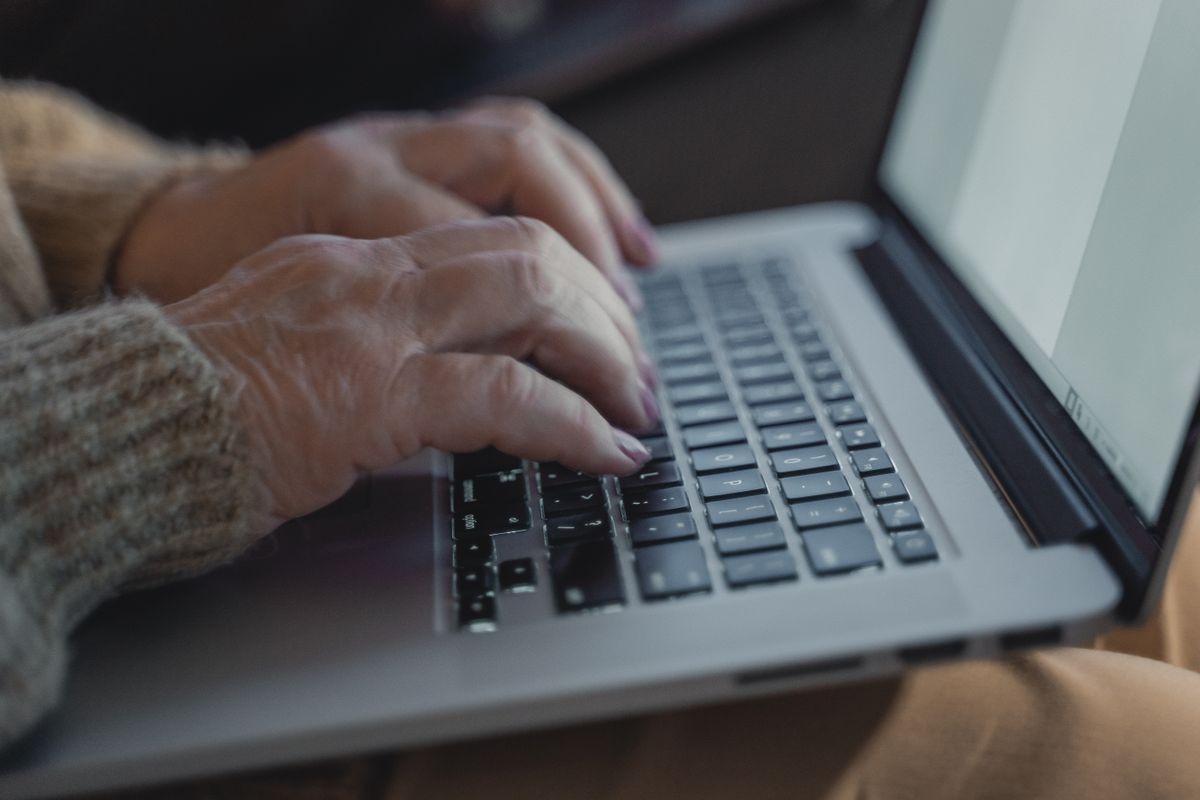 Propriétaire tapant sur un ordinateur portable pour se connecter à Airbnb et approuver la connexion du logiciel de sa conciergerie