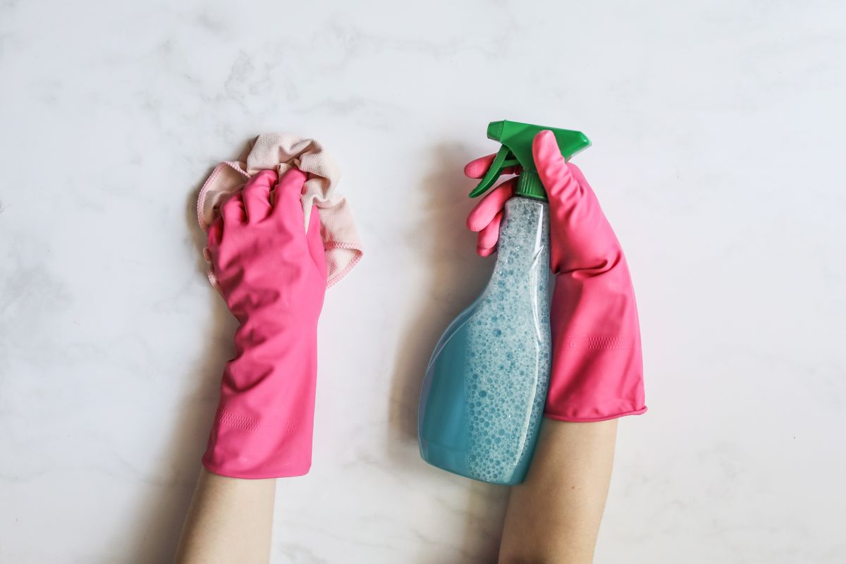 Gloved hands holding a spray bottle and a cloth, the basic kit a backup cleaner needs on site