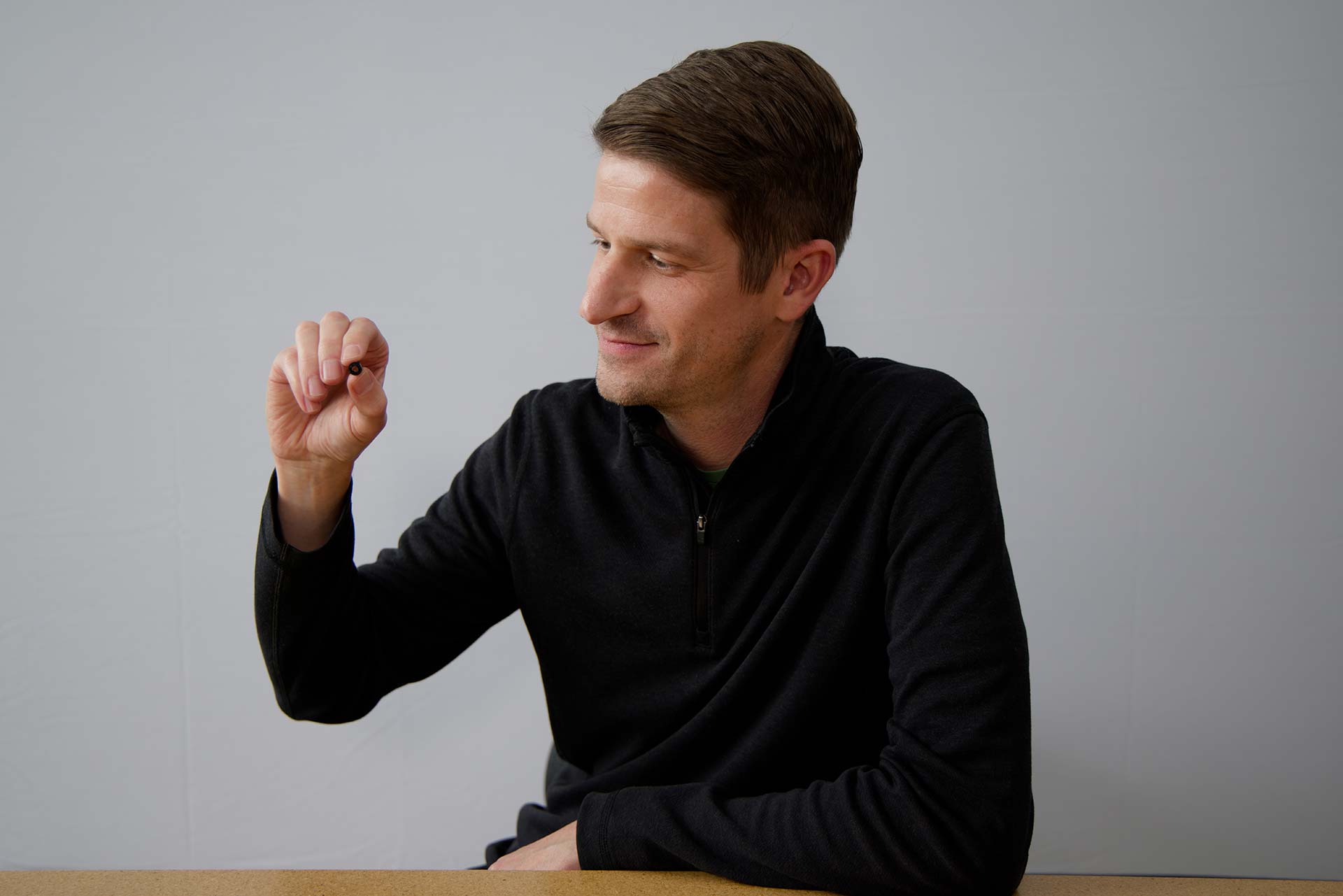 A Magic Leap engineer holds a tiny lens between his finger tips.