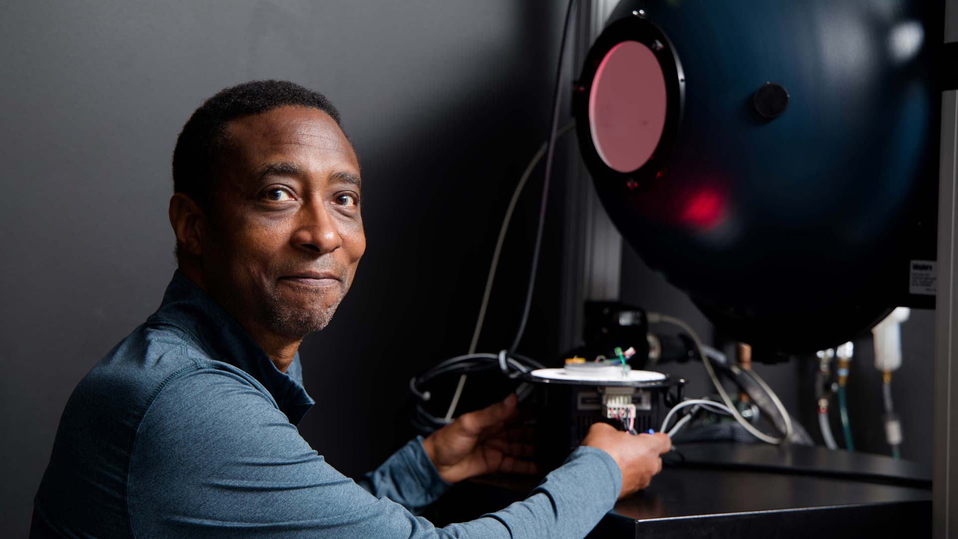 A Magic Leap technician sits in front of a metrology tool with his hands holding the controllers.