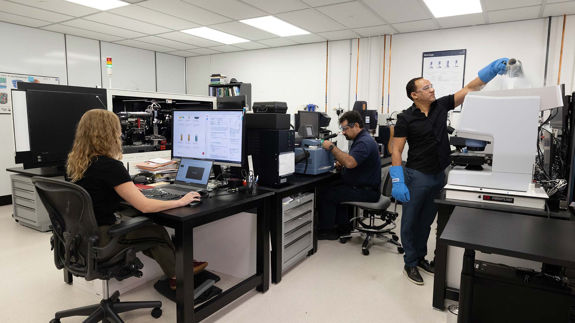 Three Magic Leap employees work in a lab with computers and specialized equipment.