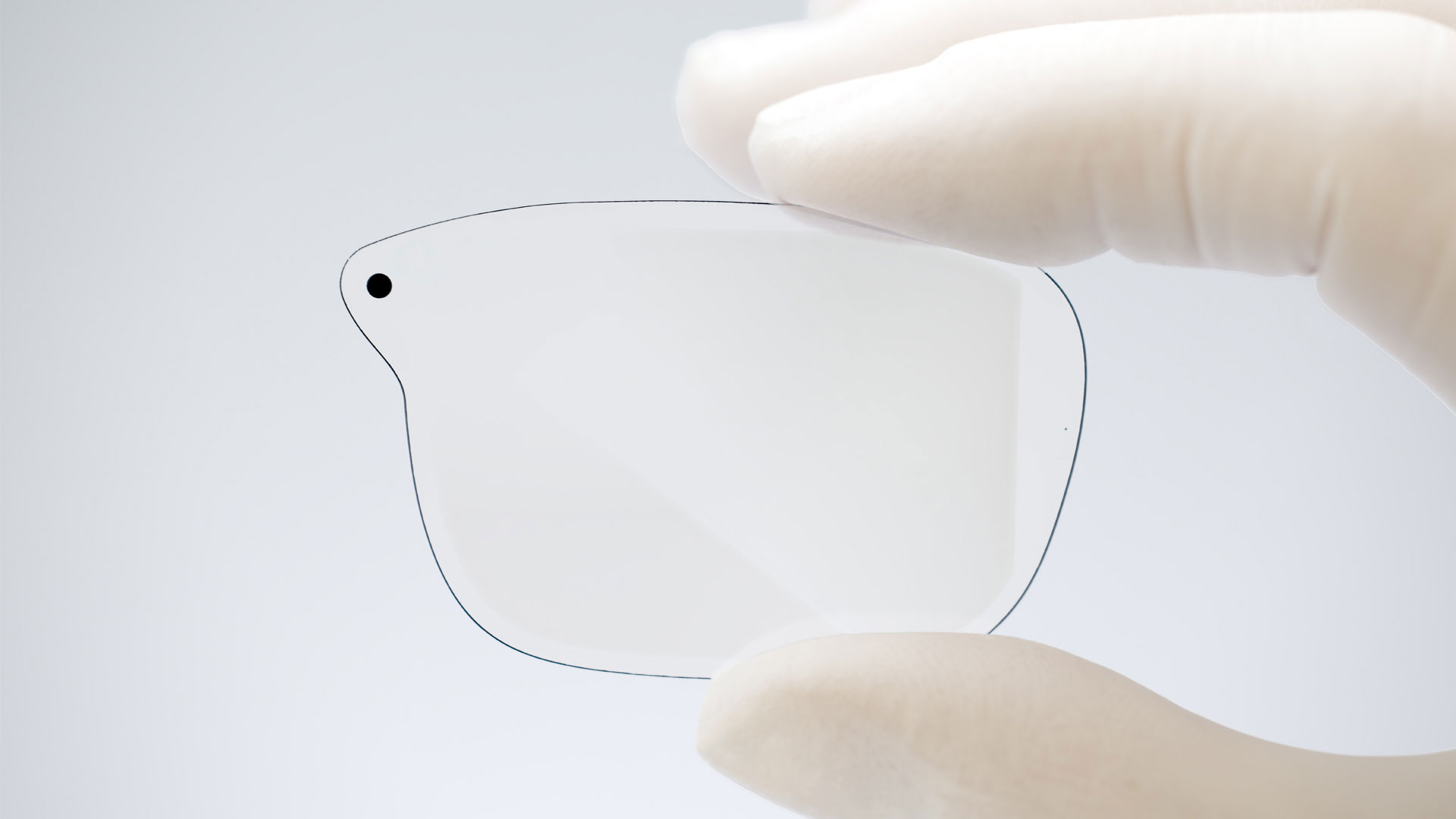 A Magic Leap engineer holds a single waveguide in a gloved hand to showcase the surface relief gratings in the waveguide.