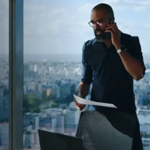 Image of a person talking on the phone in an office while holding a piece of paper
