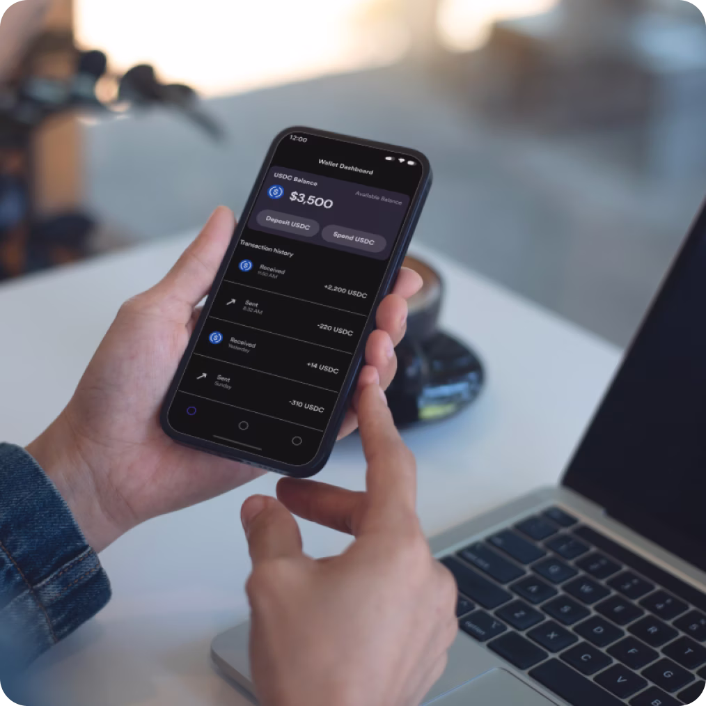 Person holding a smartphone displaying a USDC wallet app with a $3,500 balance. The screen shows options to deposit or spend USDC.