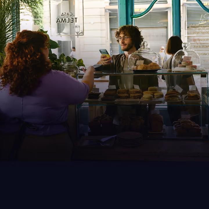 homem pedindo café em uma cafeteria e tirando uma foto da vitrine de comida
