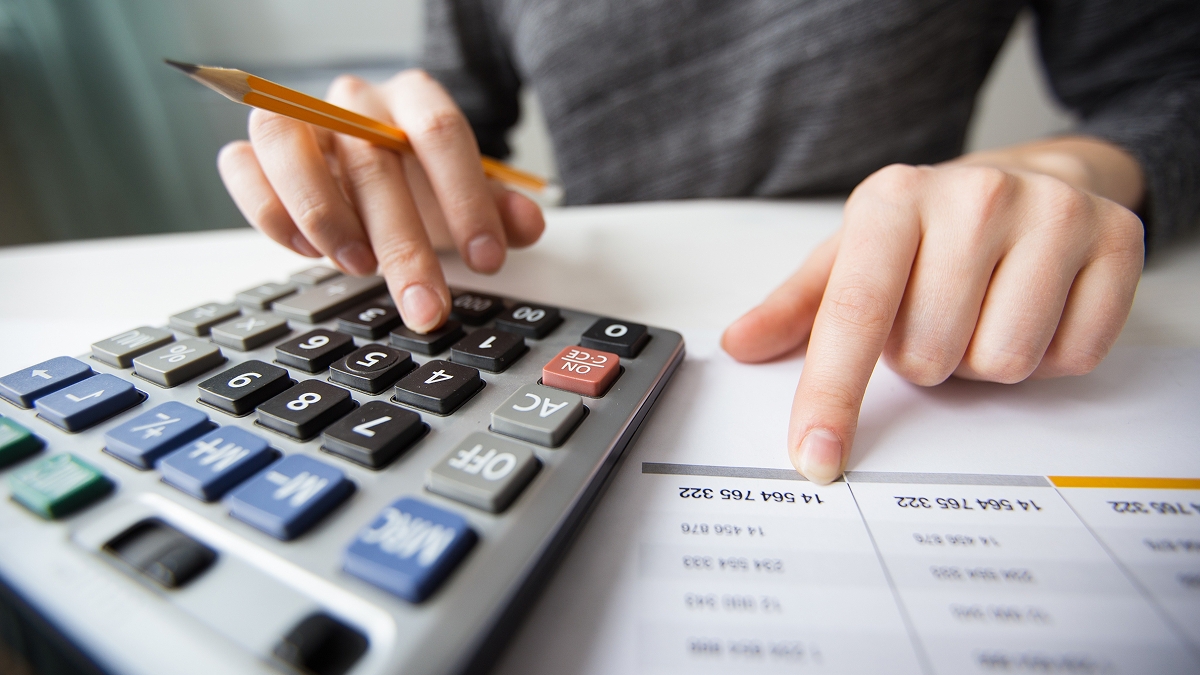 Pessoa fazendo anotações sobre preços após verificar na calculadora.
