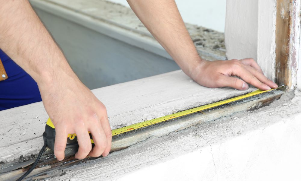 A man taking measurements for a replacement window.