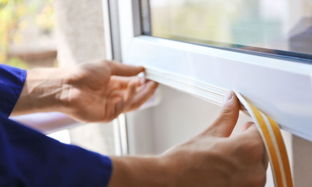 A man using a foam strip to insulate a window.