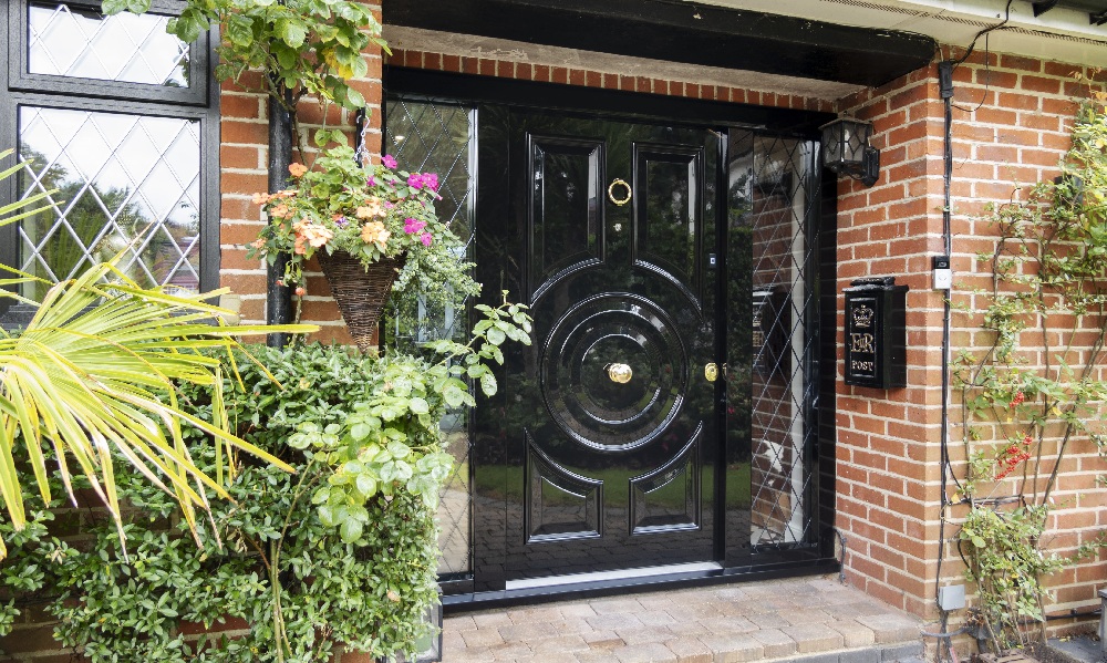 A modern security front door with a lantern-style lamp and plants for decor.
