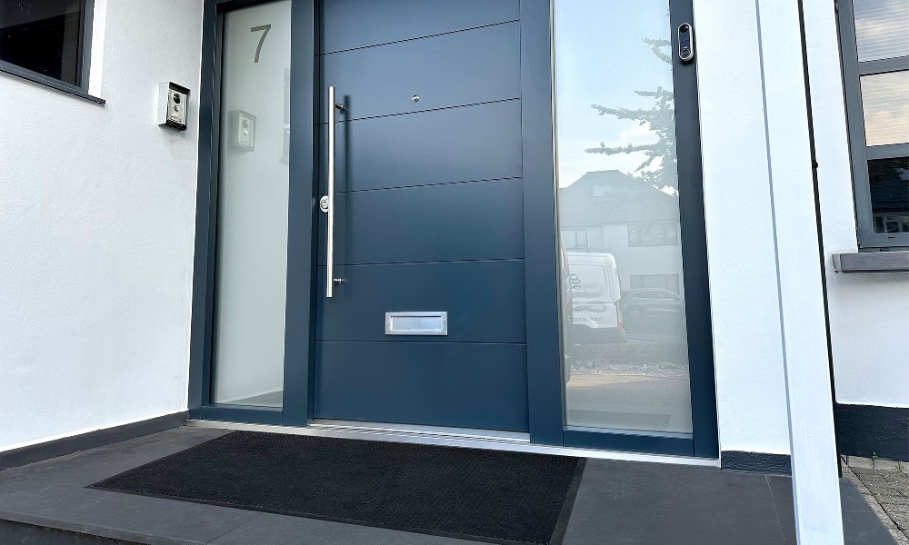 A modern front door with a doormat that compliments the door.