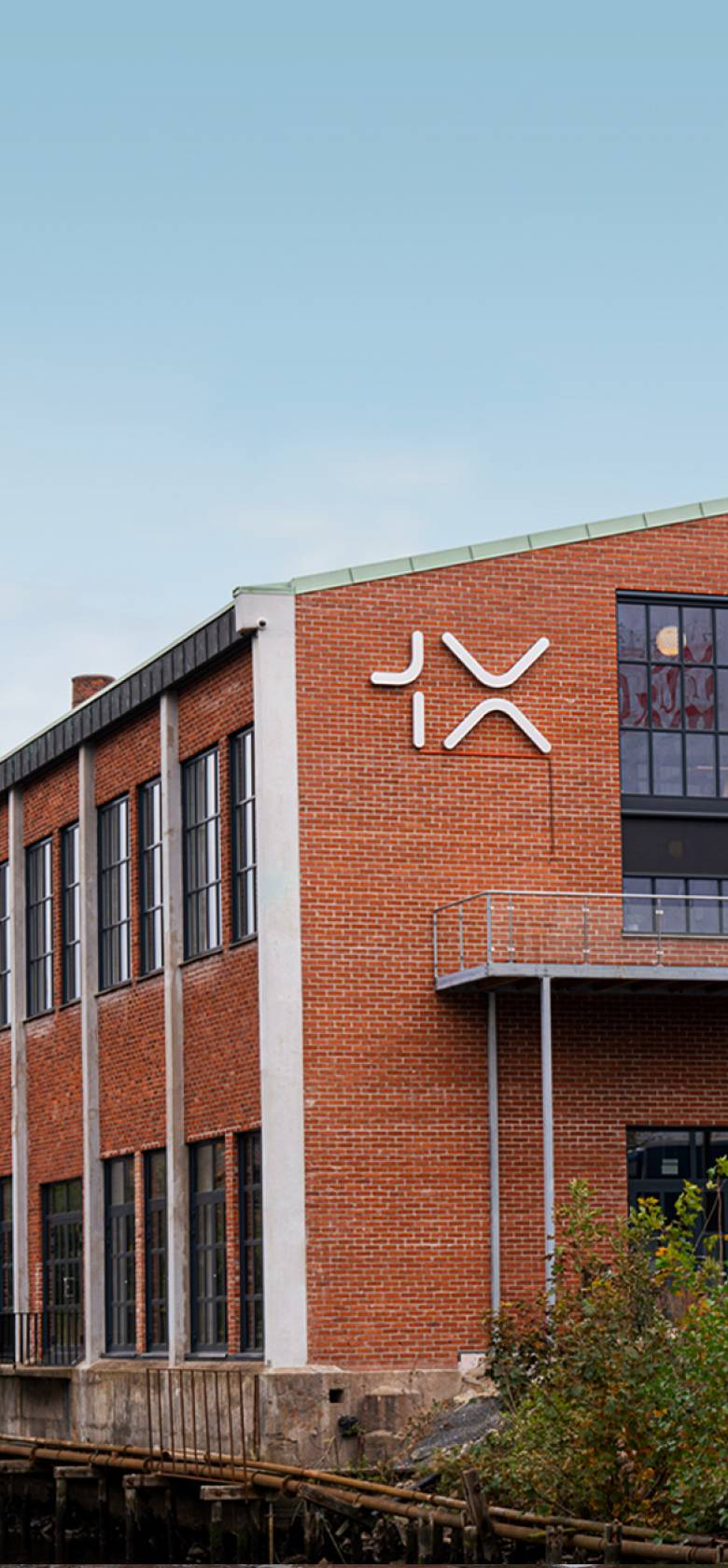 The 1X HQ located in Oslo, Norway. The building is a brick buildng by a river