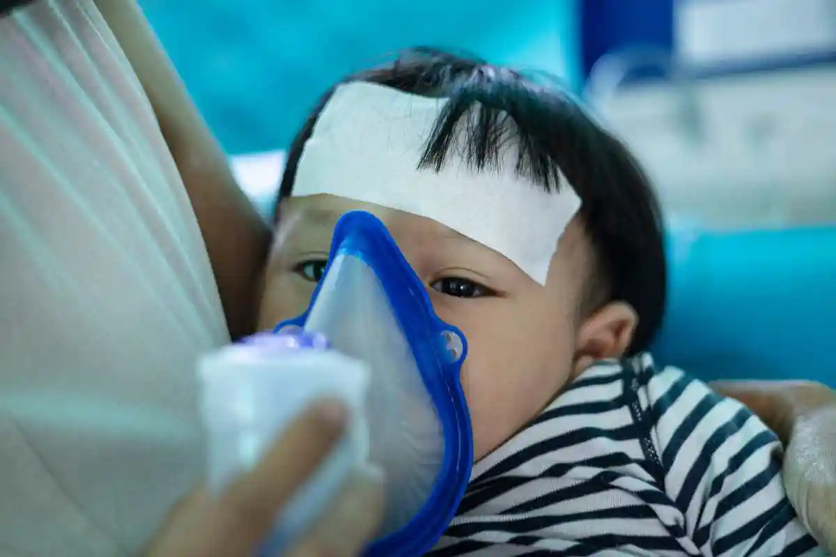 Baby with mask and inhaler respiratory health risks after smoke and flooding