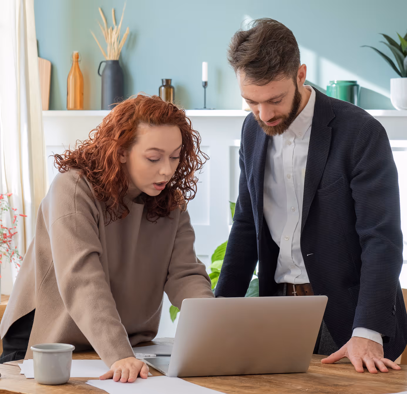 Two colleagues intensely reviewing documents and a laptop screen during a discussion in a well-lit office.