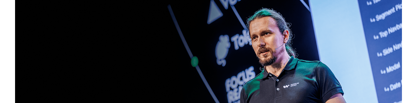 Speaker presenting on stage with a dark background.