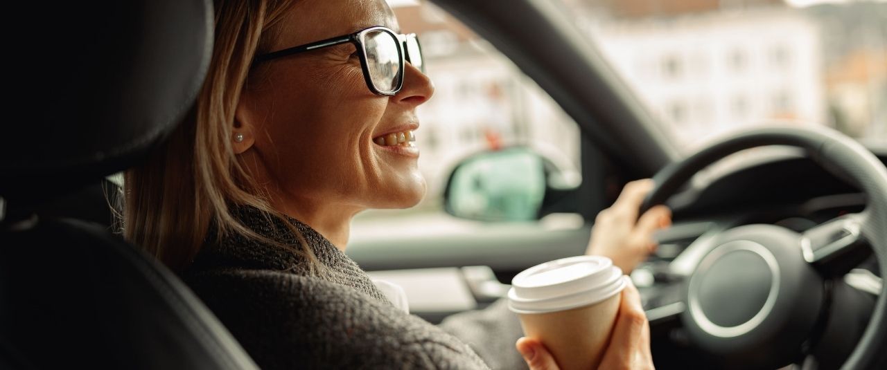 Frau mit Kaffee in der Hand in einem Auto