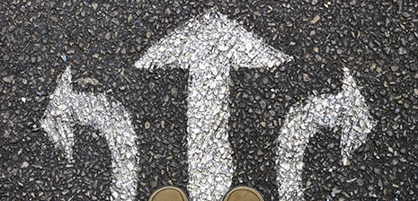 Weiße Pfeile auf Asphalt zeigen nach links, geradeaus und rechts.