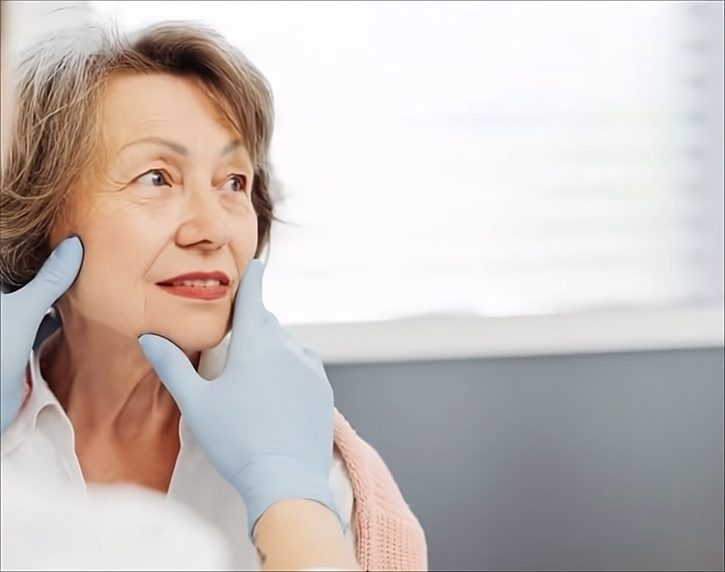 Doctor examining older woman’s face in consultation