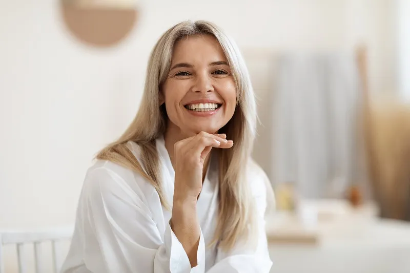 Smiling woman in light top sitting indoors