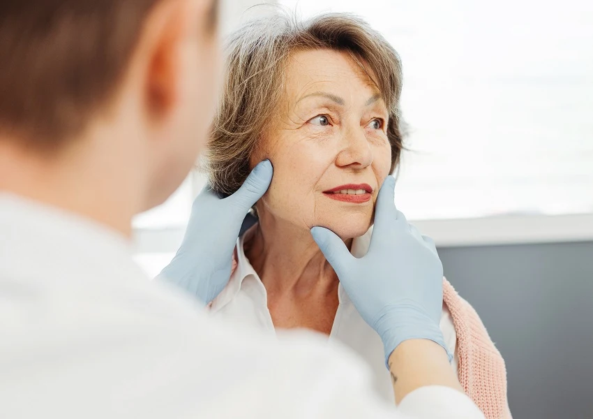 Doctor examining older woman’s face in consultation