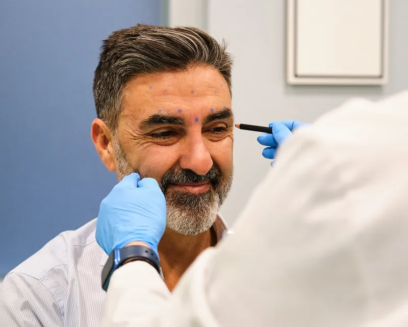 Doctor marking man's face before procedure