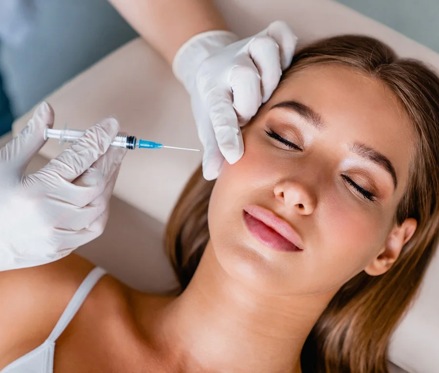 Doctor preparing cosmetic injection near woman’s jawline