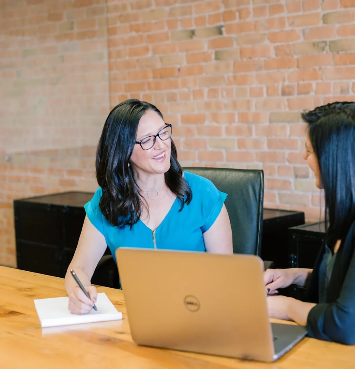 Deux femmes discutent ensemble assises devant une table avec un ordinateur