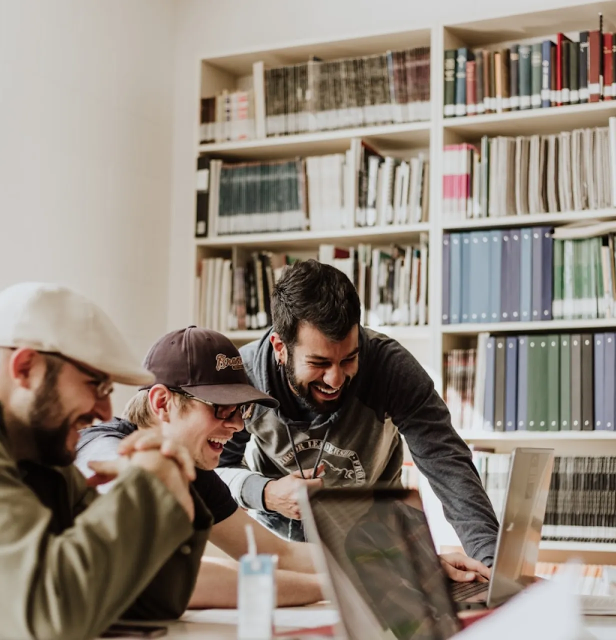 Des hommes assis autour d'une table en train de travail dans la joie avec des ordinateurs