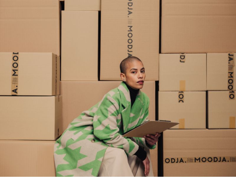 Order Fulfillment Services, Frau mit Klemmbrett vor MOODJA Kartons