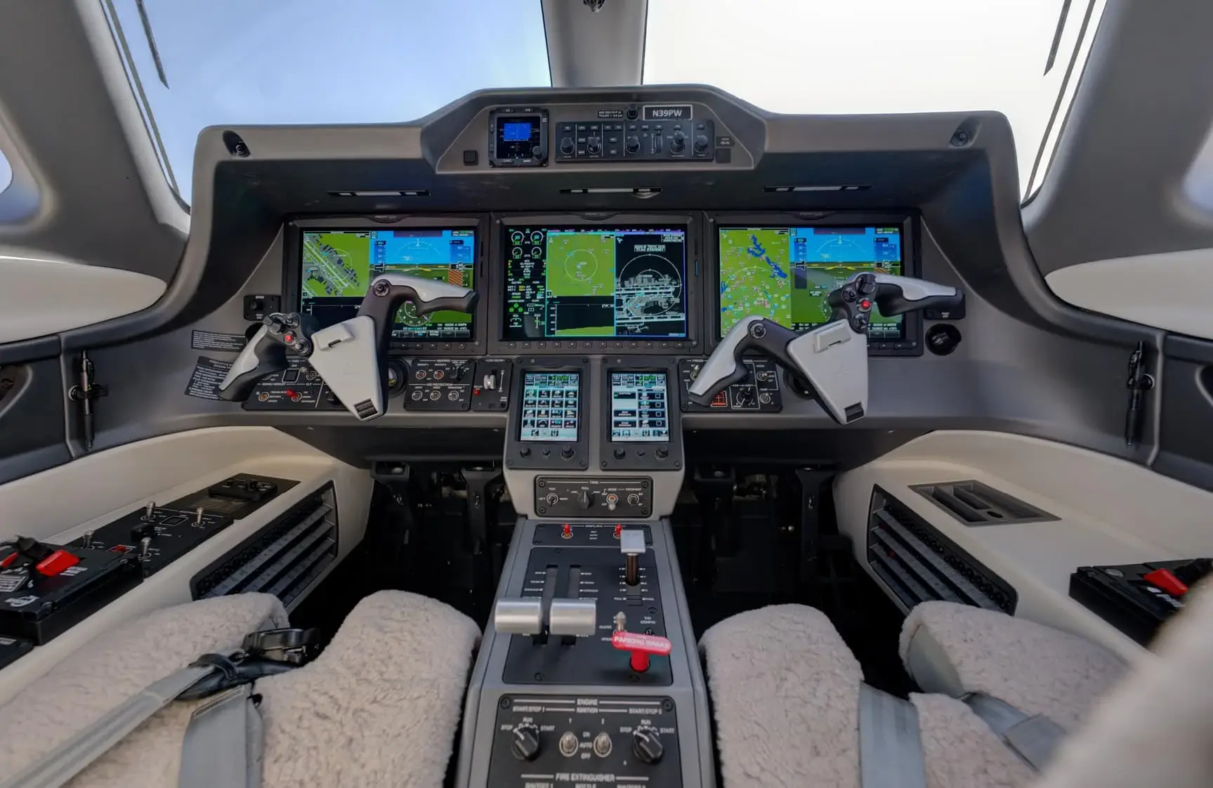 Detailed cockpit of a private jet with multiple digital flight displays and control yokes.