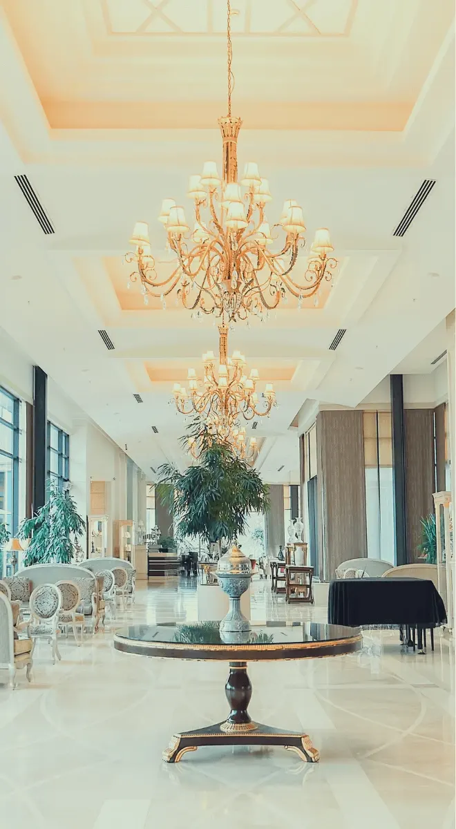 Opulent hotel or lobby interior with large chandeliers, white marble floors, and elegant furniture.