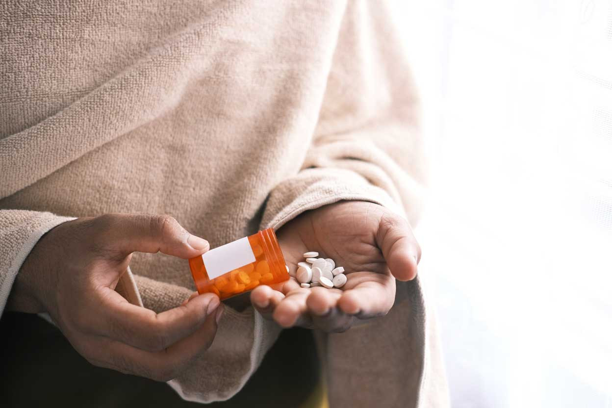 Person pouring pills from a bottle into their hand