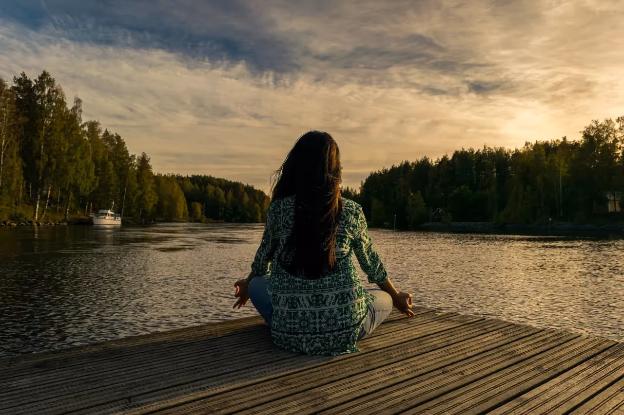 Woman meditating on a dock by the lake