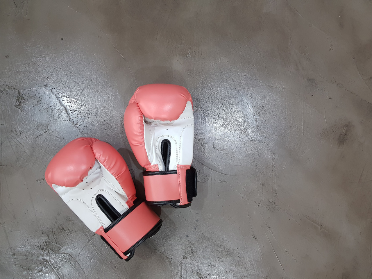 A pair of red and white boxing gloves laying on the ground.