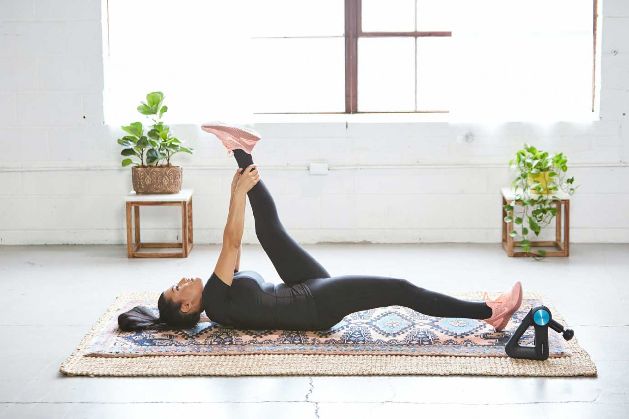 Woman laying on a rug stretching her leg out