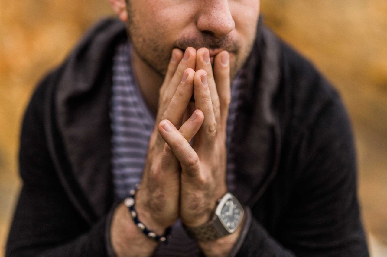 a nervous man with his hands over his mouth