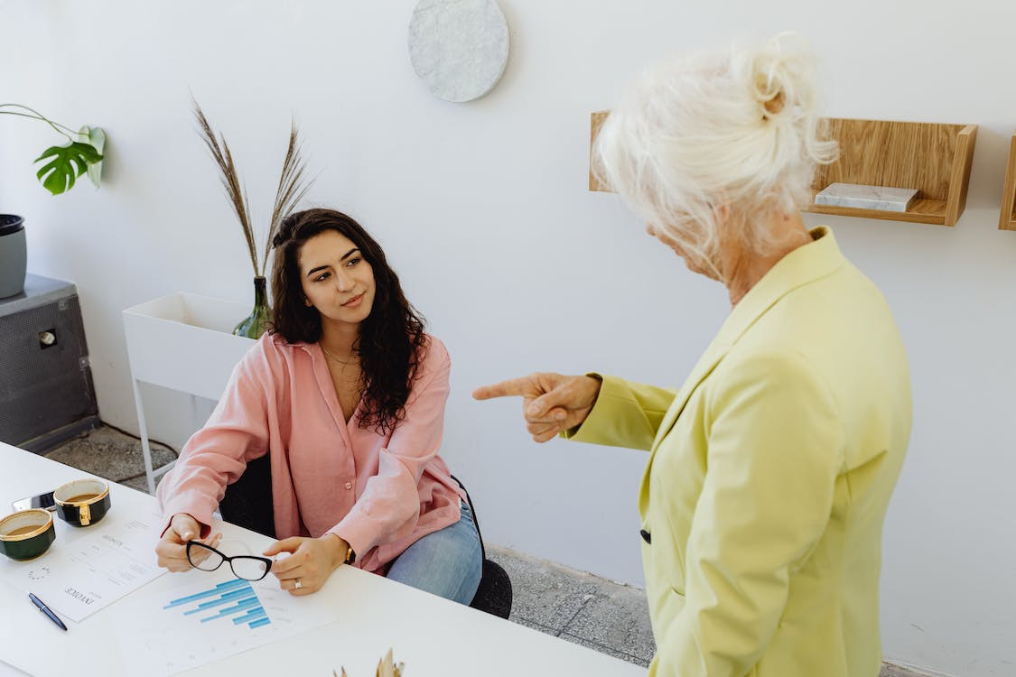 Curly Haired Woman Looking at Gray Haired Woman