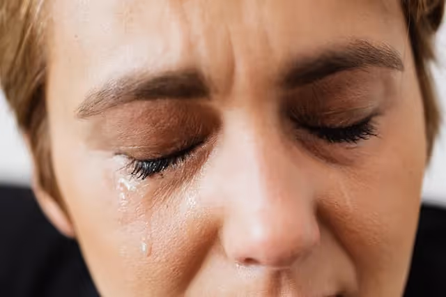 Close up of a woman with her eyes closed and tears falling down her face.
