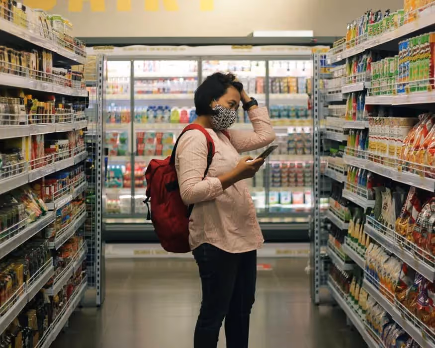 a woman with a hand on her head looking at food in a grocery store