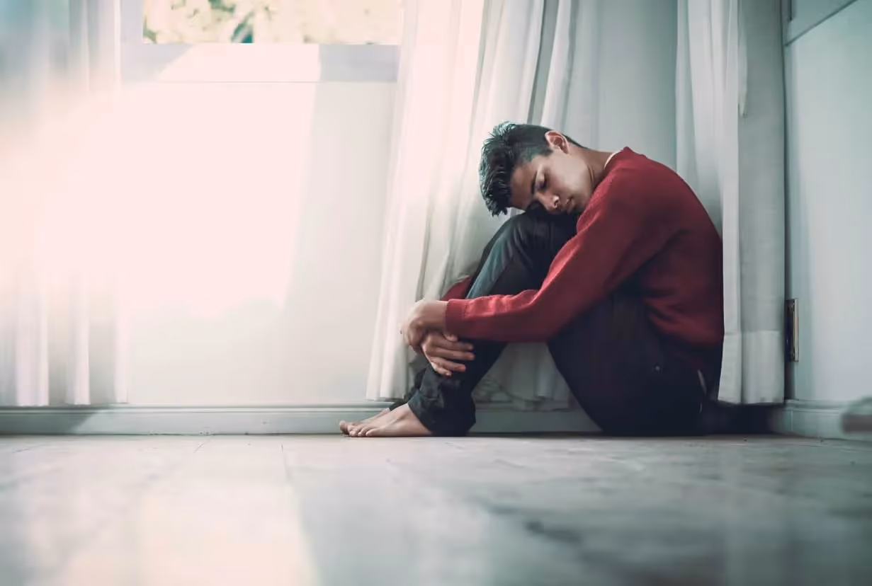 a young man on the flooring embracing themself