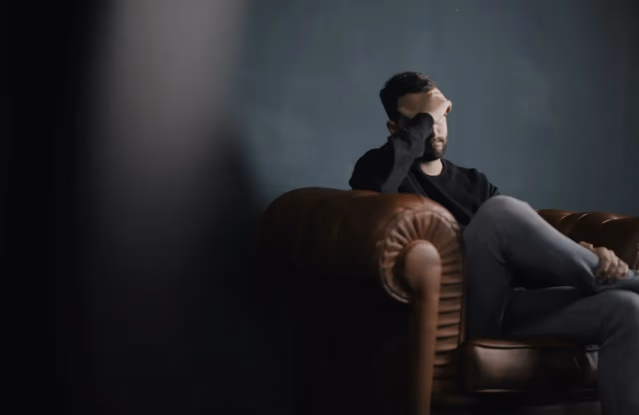 Person sitting on a couch with their hand over their face.