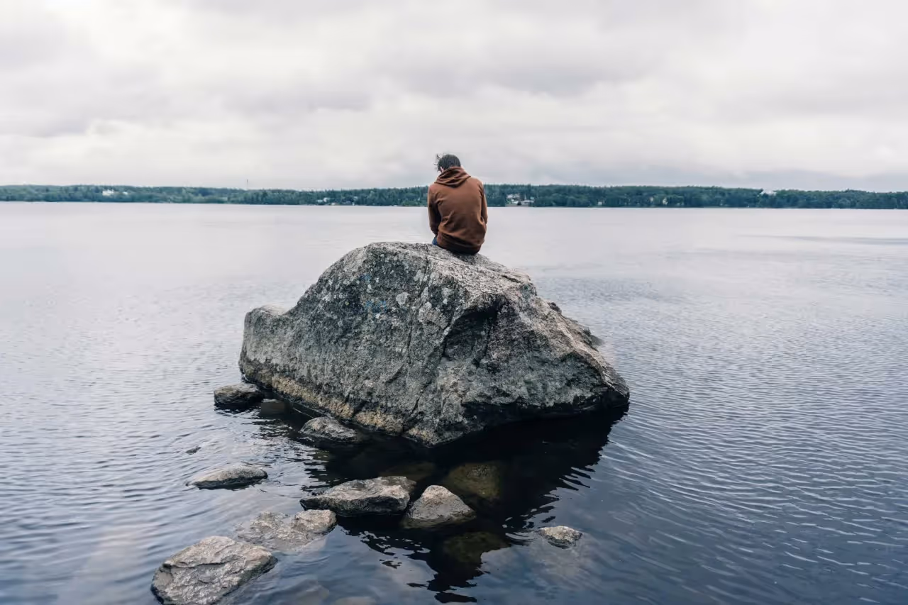 a person sitting alone on a rock