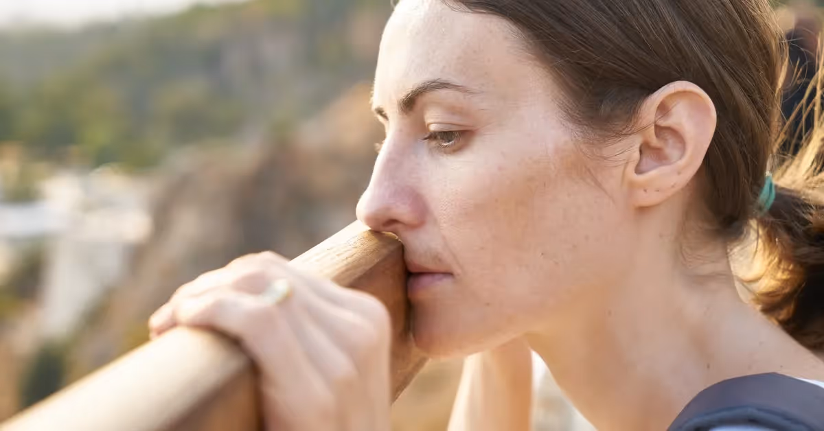 A woman contemplating how to overcome insecurity while leaning over a wood fence.