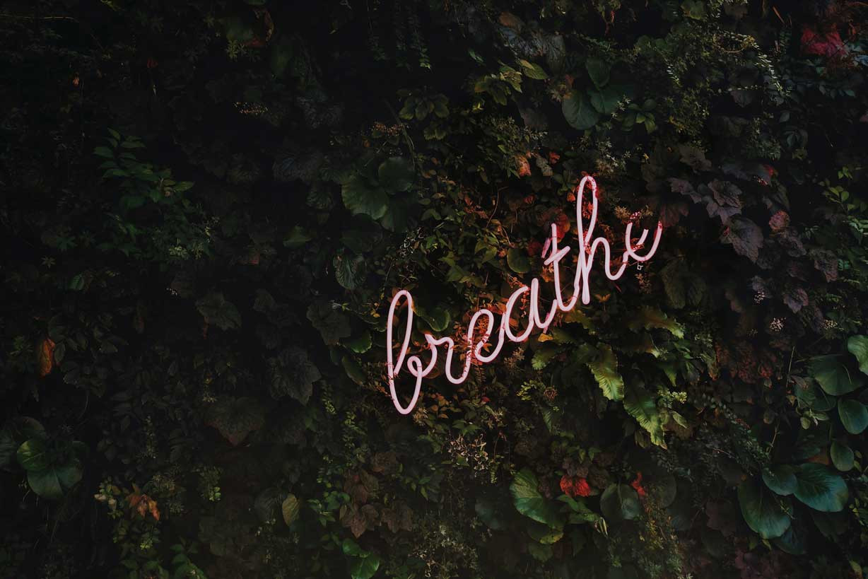 a neon sign that says breathe