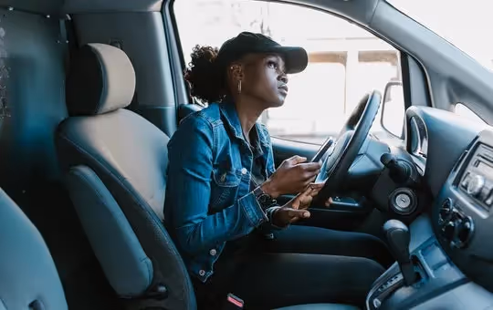 Woman sitting in her car looking at something outside.