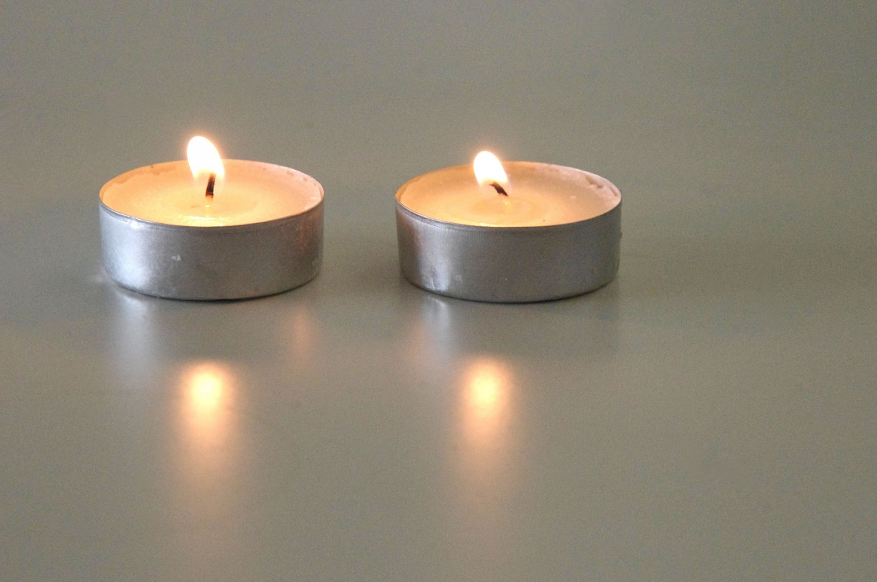 Two tea light candles sit next to each other