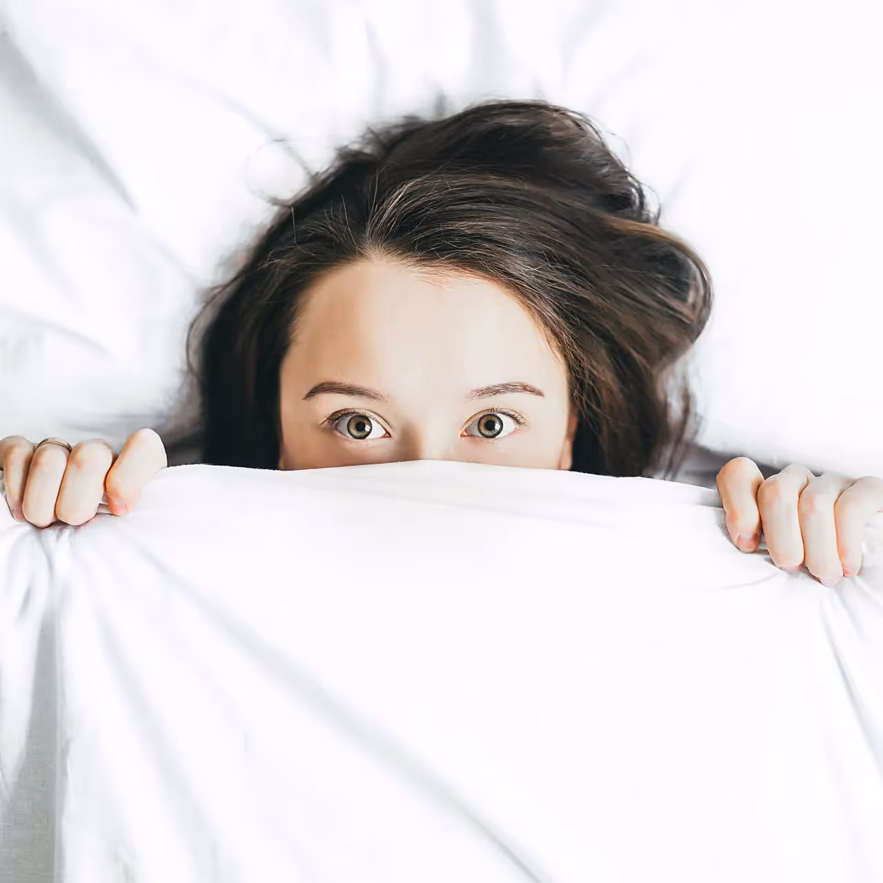 a woman hiding under a blanket