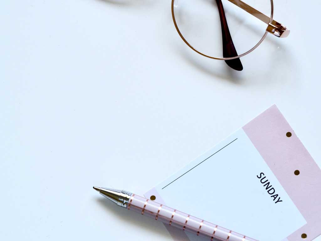 a pen glasses and calendar with a sunday on it