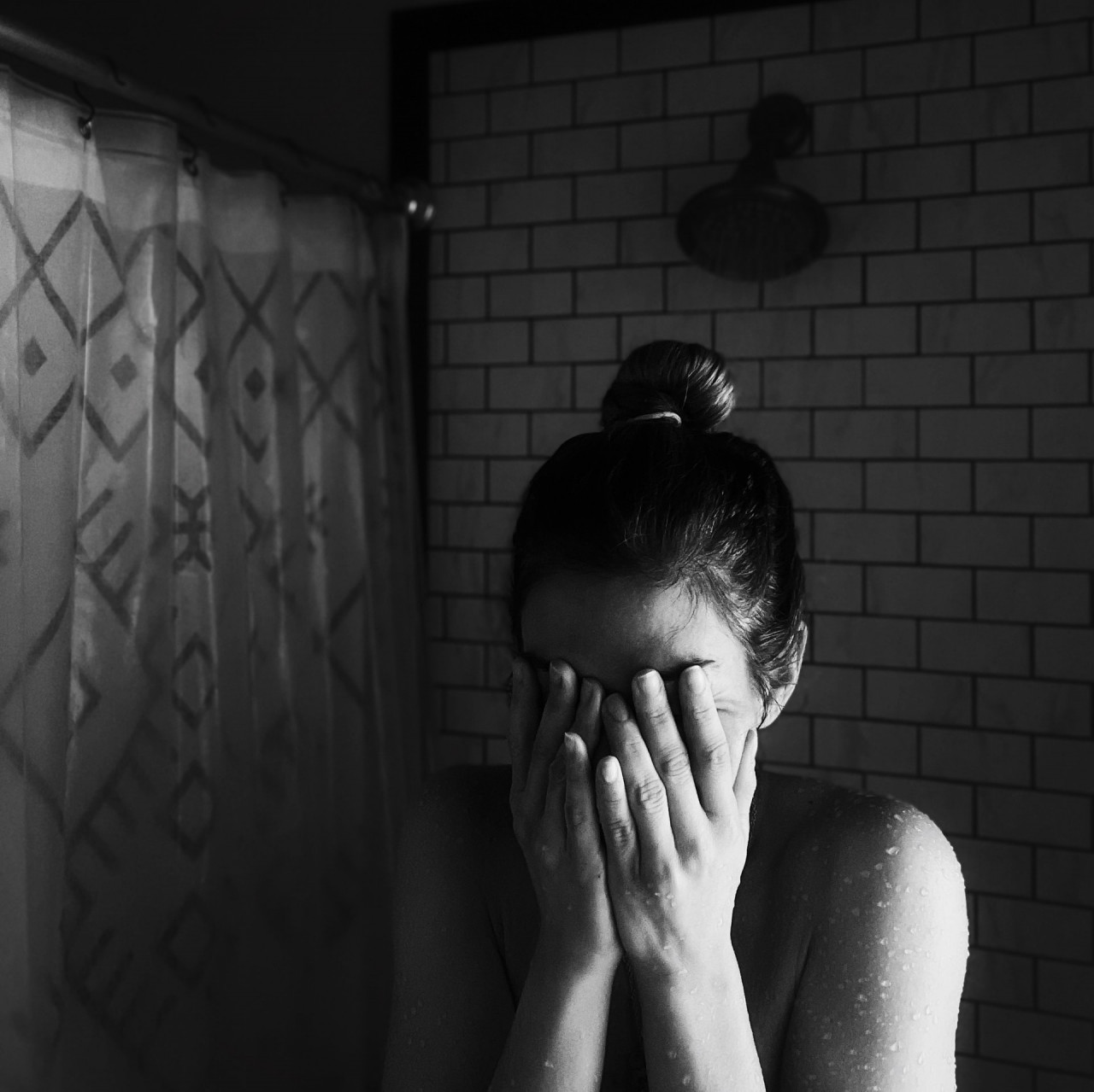 Woman standing in the shower with her hands over her face