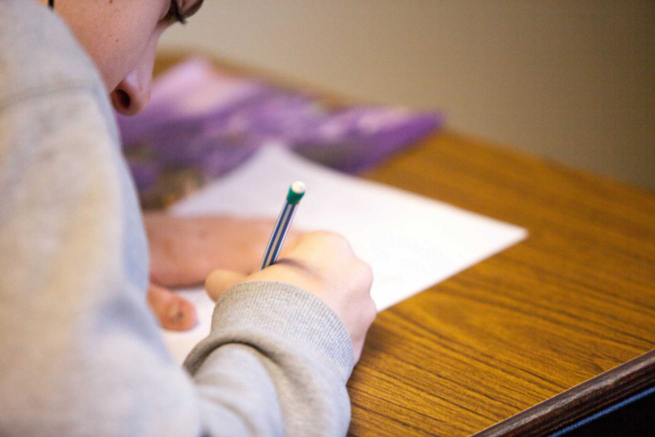 a person writing a test on a desk