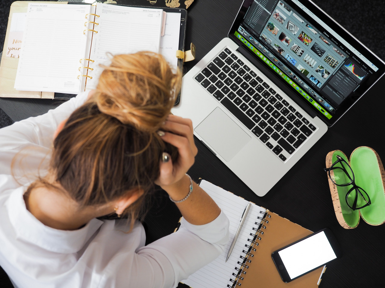 Woman sitting in front of a computer with head down.